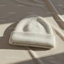Cozy white knitted beanie hat on soft fabric surface