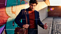 Confident man walking urban street with leather bag