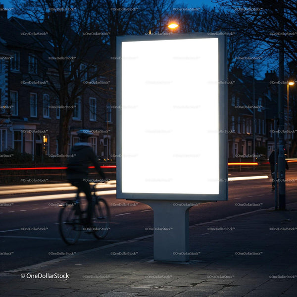 Blank illuminated billboard by city street at dusk JPG Mockup Image