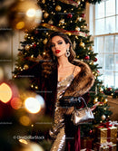 Elegant woman in gold dress by decorated Christmas tree