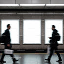 Blurred commuters walking past empty subway ads