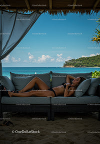 Relaxing Woman Sunbathing on Outdoor Sofa with Ocean View