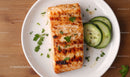 Grilled Salmon with Fresh Cucumber Slices and Herbs on White Plate