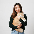 Smiling woman holding a fluffy cream cat close
