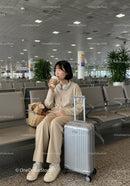 Young Woman Relaxing in Airport Lounge with Suitcase and Coffee