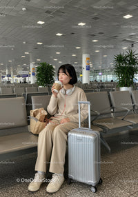 Young Woman Relaxing in Airport Lounge with Suitcase and Coffee
