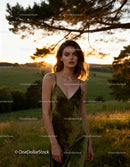 Young woman in green dress standing in golden hour field