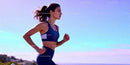 Focused young woman running outdoors at sunset