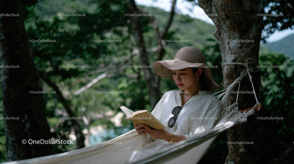 Woman Relaxing in Hammock Reading in Green Forest Scene