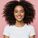 Young Woman with Curly Hair Smiling Against Pink Background