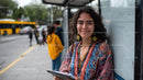 Young Woman Smiling at City Bus Stop with Tablet During Day