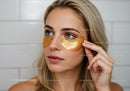 Bright Young Woman Applying Gold Under Eye Patches for Skin Rejuvenation