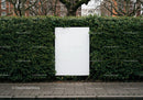 Blank white billboard framed by lush green hedge