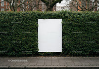 Blank white billboard framed by lush green hedge