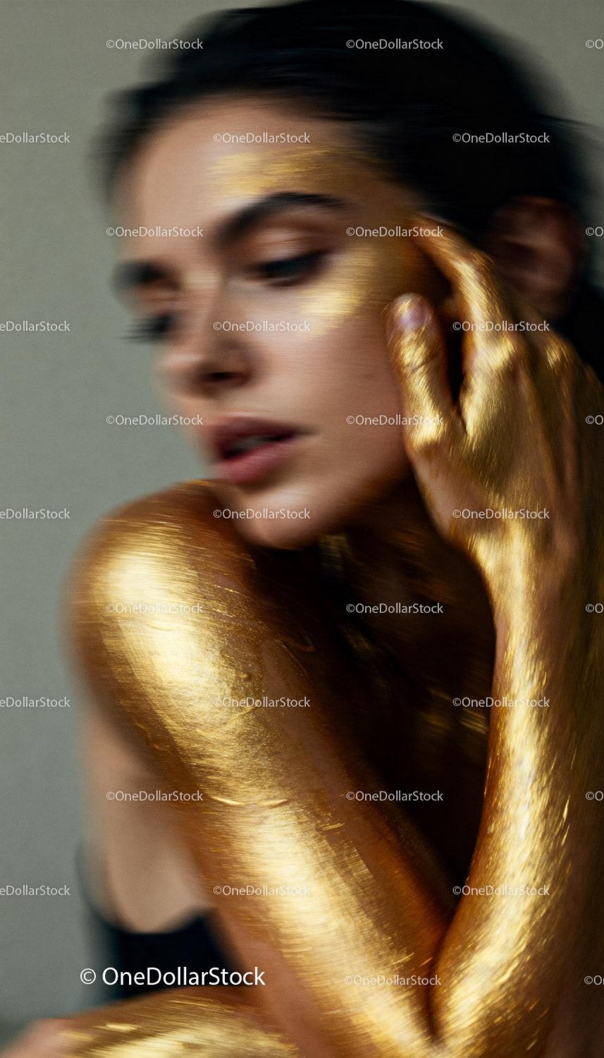 Blurred portrait of woman with golden body paint