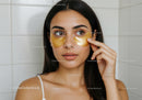 Young Woman Applying Gold Under-Eye Collagen Masks for Skincare