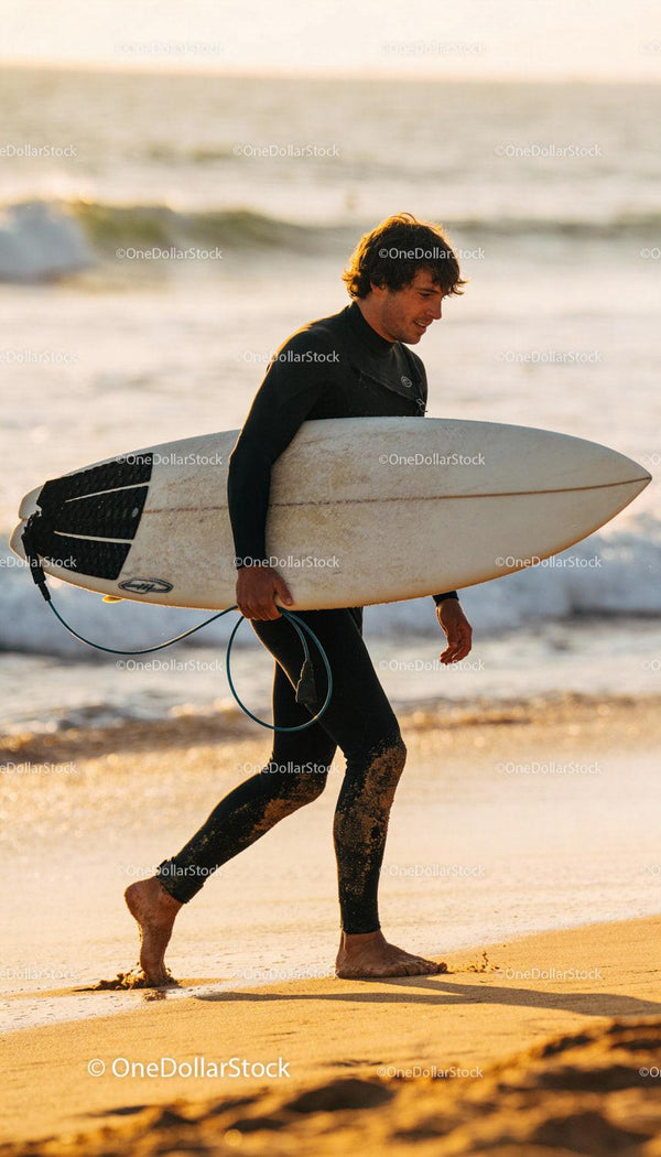 Surfer Walking on Beach with Board at Golden Hour