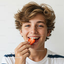 Smiling Young Boy Enjoying Strawberry Against Bright Background