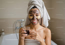 Woman with Facial Mask and Bathrobe Holding Skincare Product