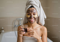 Woman with Facial Mask and Bathrobe Holding Skincare Product