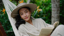 Young Woman Relaxing in Tropical Garden Hammock Reading Book