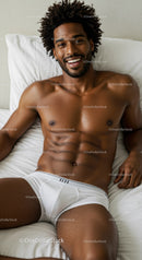 Smiling man relaxing in white underwear on bed