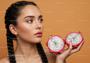 Young Woman Holding Halved Dragon Fruit on Vibrant Background