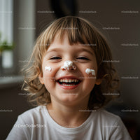 Happy child with cream on face laughing indoors