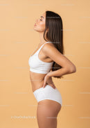 Young Woman in White Sportswear Posing in Minimalist Studio