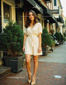 Stylish Young Woman in Beige Dress Walking on City Street During Day