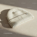 Cozy cream knit beanie hat on textured fabric surface