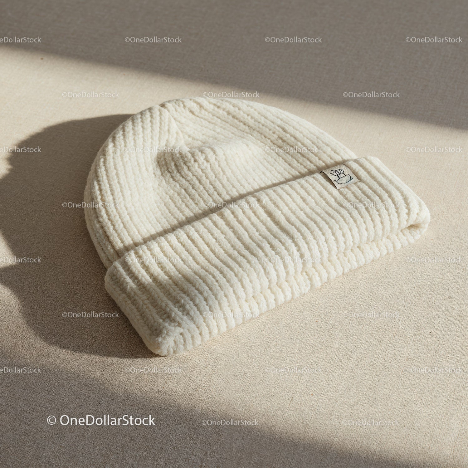 Cozy cream knit beanie hat on textured fabric surface