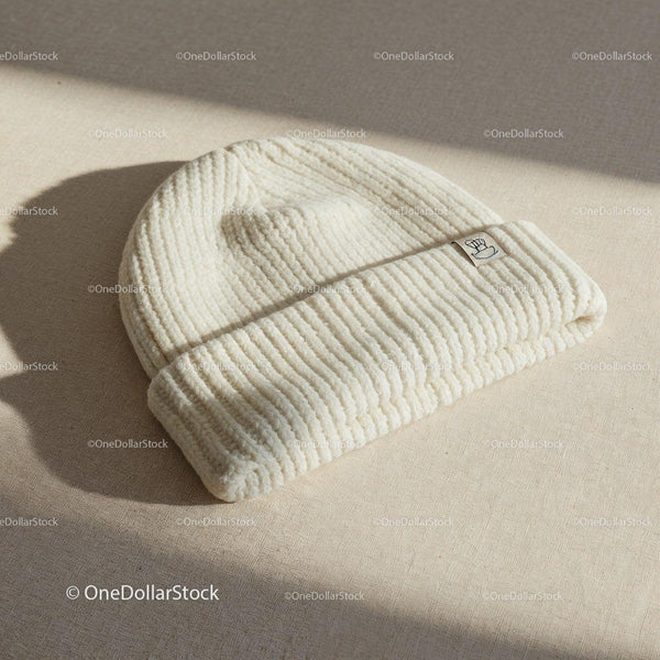 Cozy cream knit beanie hat on textured fabric surface JPG Mockup Image