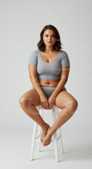 Confident Woman Sitting on Stool Wearing Gray Crop Top and Shorts