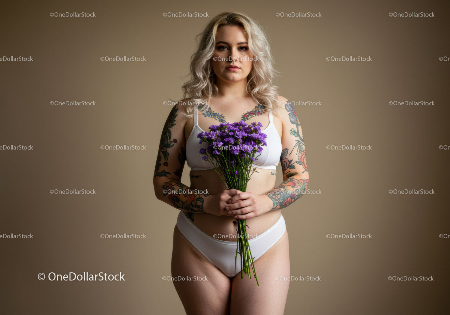 Tattooed Woman in White Lingerie Holding Purple Flowers in Studio