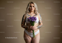 Tattooed Woman in White Lingerie Holding Purple Flowers in Studio