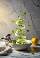 Fresh cucumber ribbon and herbs spiraling over bowl