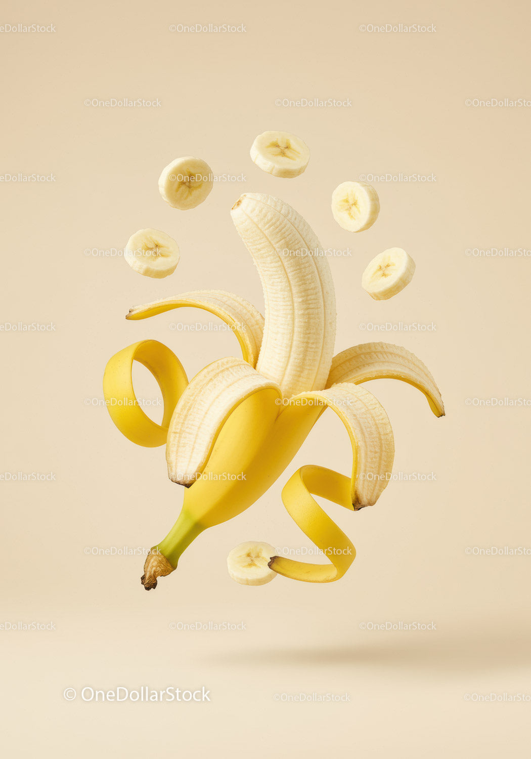 Peeled banana with floating slices on beige background