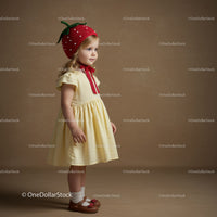 Little girl wearing strawberry hat and yellow dress