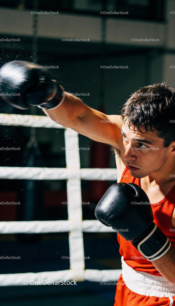 Focused Male Boxer Training Intense Punch in Gym Ring