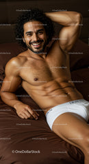 Smiling man relaxing on bed in white underwear