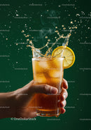 Hand holding iced tea with lemon splash on green background