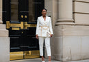 Elegant woman in white suit posing by classic entrance