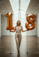 Elegant woman holding large number 18 balloons indoors