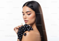Elegant Woman with Long Dark Hair Holding Black Grapes in Studio