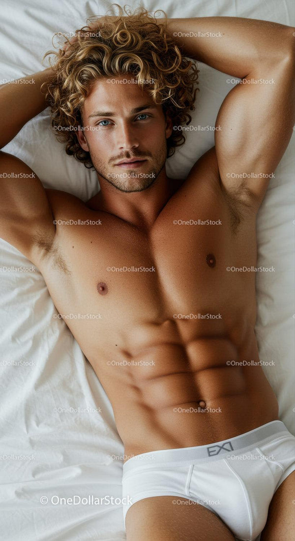 Fit young man with curly hair lying on bed in white briefs