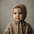 Cute toddler wearing knitted bonnet and sweater