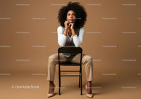 Confident Woman in Stylish Outfit Sitting on a Chair in Studio