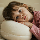 Thoughtful child resting head on soft white cushion