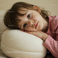 Thoughtful child resting head on soft white cushion